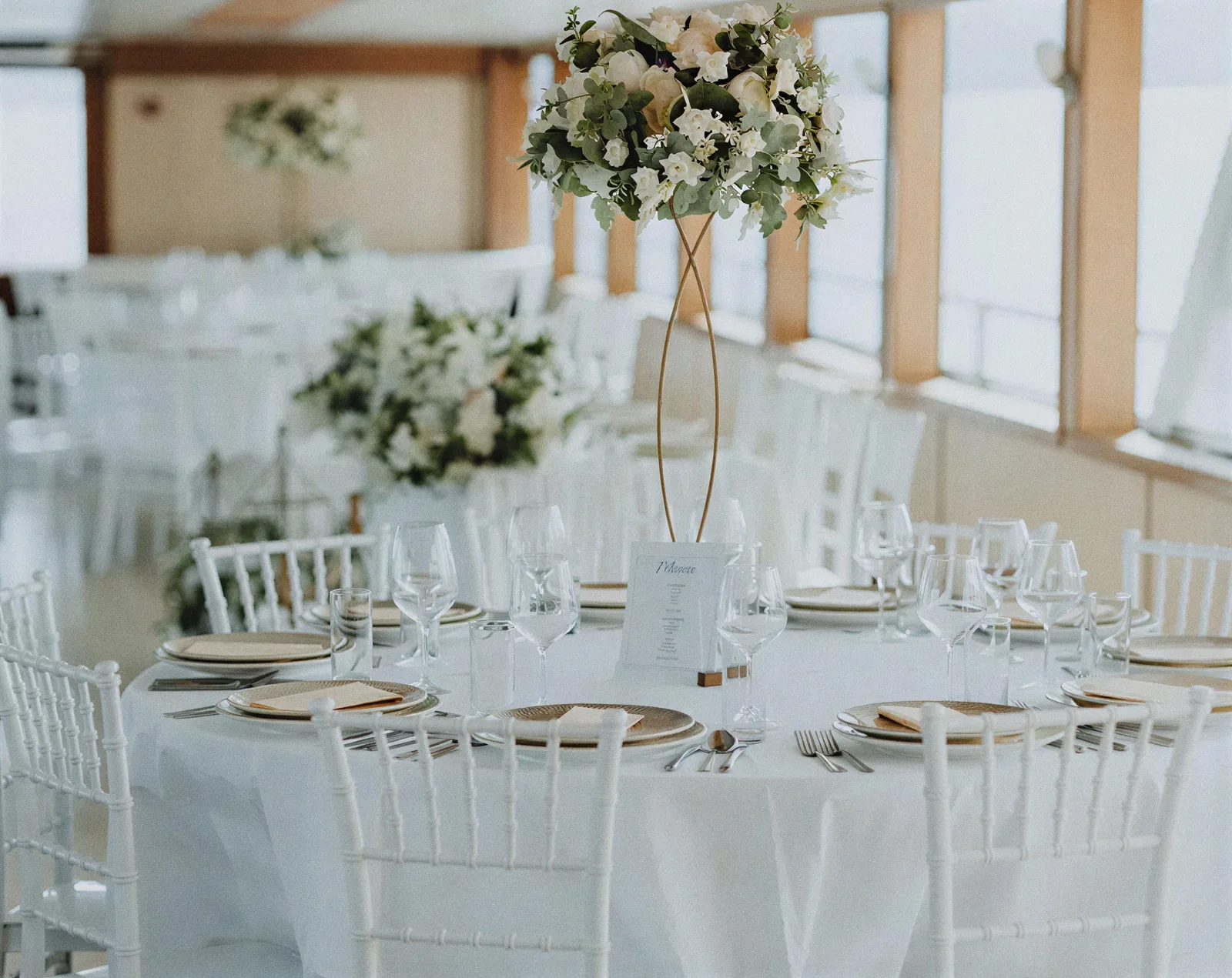 A round table set with white flowers and a menu card for a wedding on a private boat hire in Montenegro
